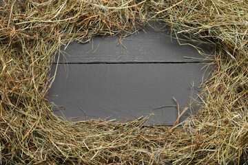 Frame made of dried hay on grey wooden table, top view. Space for text