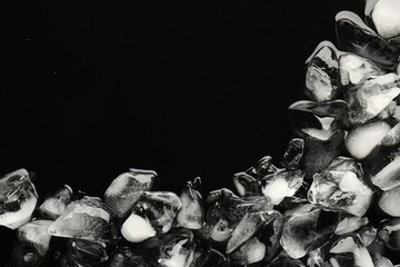 Pieces of crushed ice on black background, top view. Space for text