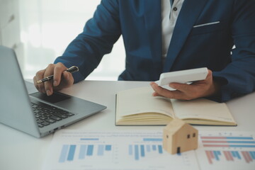 Businessmen holding pens, signing home titles with insurance, care about real estate services and the idea of real estate agents offering interest in installments to their customers.