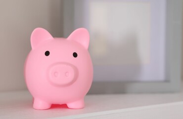 Pink piggy bank on white table, space for text