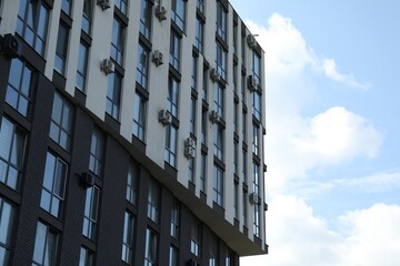 Modern building with big windows against blue sky outdoors, space for text