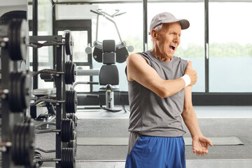 Elderly man at a gym holding his painful shoulder