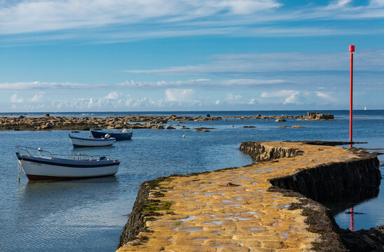 A yellow stone pier jutting out into the blue sea. Point Penmarc'h, Brittany, France.