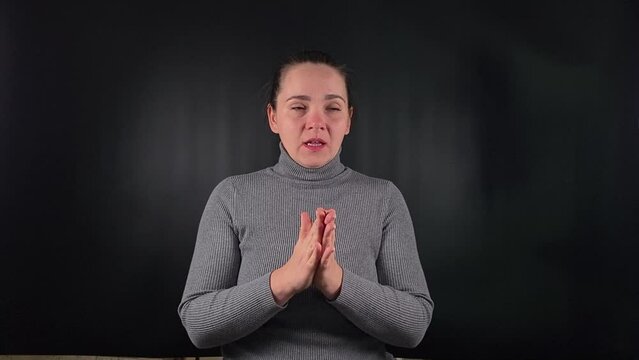 Portrait a young woman wearing gray sweater sneezing isolated on a black background indoors. The bodily reaction of a sneeze caused by illness, cold or allergies. Healthcare, respiratory issues