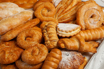 Collection of cakes and different pies with cheese, apple, cherry, meat and cabbage on a plate.