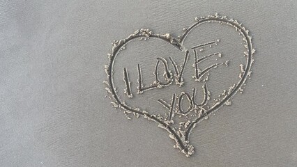 I love you written in the sand inside a heart on the beach