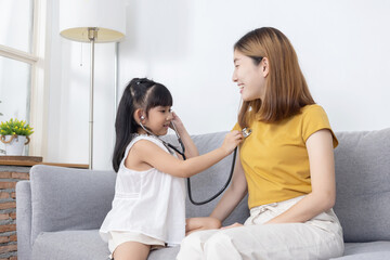 Asian daughter play  as a doctor checking up her mother in the living room