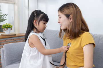 Asian daughter play  as a doctor checking up her mother in the living room