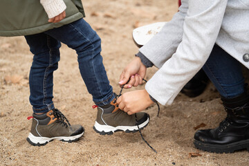 Close up of mother helping her child tying the shoes