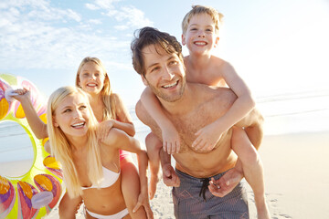 Playing, piggyback and family with kids at beach in swimsuit for holiday trip, summer vacation or weekend getaway. Love, happy parents and children for travel, adventure or bonding together at sea