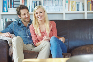 Obraz premium Smile, hug and happy couple on couch with romance, care and bonding in home lounge. Embrace, man and woman on sofa relaxing, love and enjoying conversation, relationship and weekend in living room