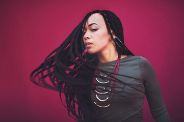 Woman, portrait and braids with hair flip, jewelry or cosmetics in fashion or beauty on a studio background. Young model or female person with wavy or long braided hairstyle, makeup or extensions