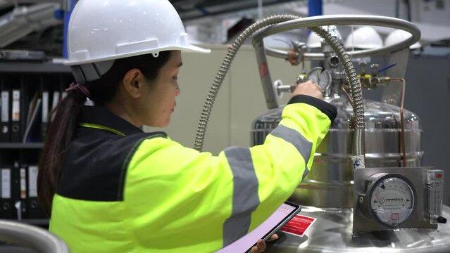 A Factory Engineer Checking Liquid Helium Levels in Storage Tanks, Ensuring Safety Compliance and Recording Usage for Machinery Operations in the Facility