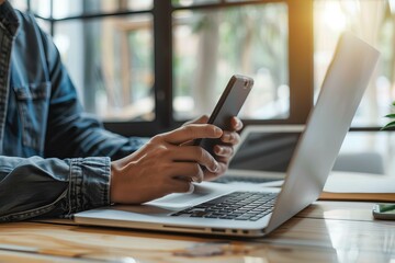Person using cell phone while sitting at laptop