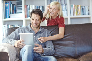 Happy, couple and home sofa with tablet or relaxing online, people smile and internet browse...