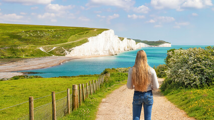 A blonde woman looks at a view of the White cliffs of Dover in Sussex, England.