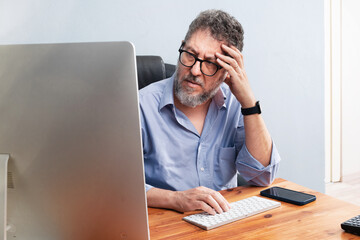 Professional businessman looking stressed while working at a computer in his office - Corporate...