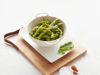 close up view of boiled edamame soybeans in a bowl seasoned with salt and spices, ready to eat.