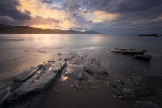 warm and dramatic sunset with rocks in the foreground on Lastron beach in Muskiz, Bizkaia