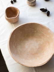An empty ceramic tile on a white linen tablecloth. Flat layout, top view. A place to record. The plate is brown, natural color. Natural clay.