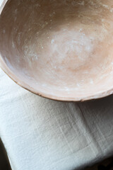 An empty ceramic tile on a white linen tablecloth. Close-up. Flat layout, top view. A place to record. The plate is brown, natural color. Natural clay.