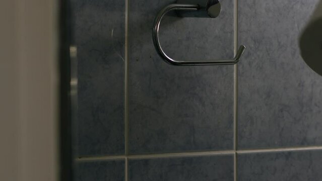 Hand changing toilet roll in bathroom 