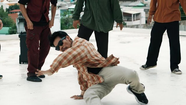 Professional hispanic break dancer practice B boy dance while multicultural friends at roof top. Young modern dancing group doing hip hop movement. Style,fashion,action. Outdoor sport 2024. hiphop.