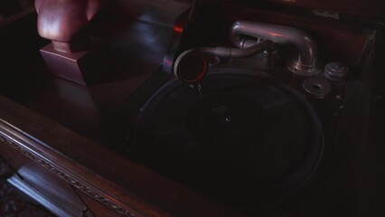 This video shows a close up view of an antique phonograph playing in moody lighting. 