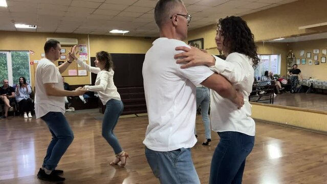  Smiling adults dancing salsa together in dance studio