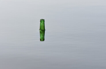 reflection of the neck of a green glass bottle sticking out of the water