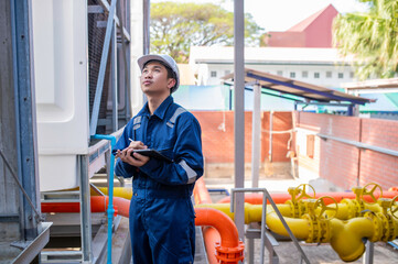Young engineer working at large factory,Technician in protective uniform and with hardhat  checking...