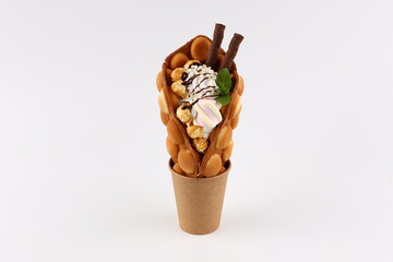 Trendy Hong Kong bubble waffles with ice cream, cream and berries on white wooden background. Copy...