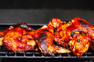 Barbequed chicken wings on a gas grill  blackened char marks.