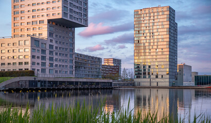 the lakeside tower apartment buildings and wave with reflection in Almere at sunset, modern building on water