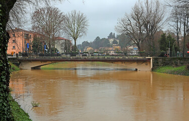 bridge over the river overflowing with muddy water about to overflow the banks in the city of...