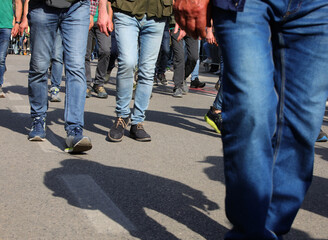 men walking on the street in jeans during a workers strike with their faces invisible