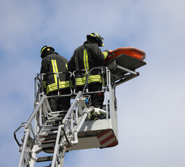 Firefighters on board an aerial platform with stretcher during the rescue of the injured person