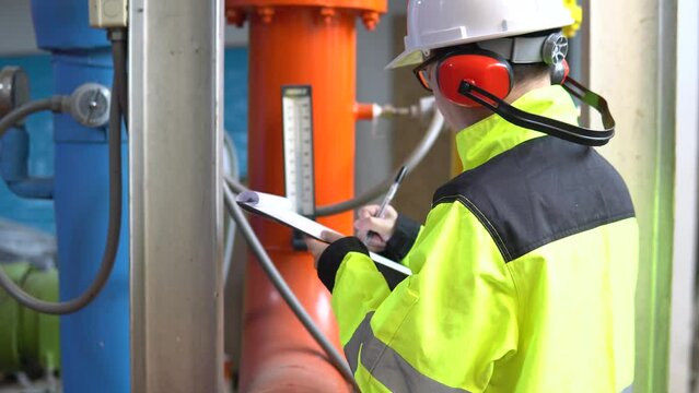 Factory engineer inspecting the cooling room with a cooling system,checking equipment performance,ensuring proper operation of the cooling system,efficient temperature control in the industrial plant.