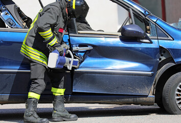 Firefighter using powerful hydraulic shears to pry open the blocked door of a wrecked car