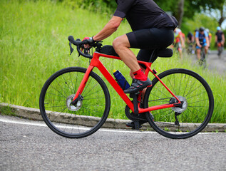 cyclist powerfully pedaling a red road bike during a road race