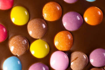 Multi-colored candies in sugar glaze in a large chocolate bar