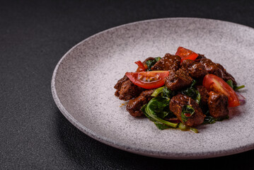 Delicious warm salad with pieces of meat, spinach, tomatoes, salt, spices and herbs