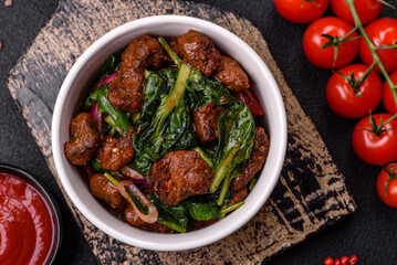 Delicious warm salad with pieces of meat, spinach, tomatoes, salt, spices and herbs