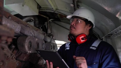 Industrial engineers,technicians,and supervisors inspecting and repairing machinery in the engine room,servicing and maintaining large locomotive engines,ensuring optimal performance and reliability i