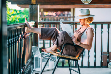 A woman is sitting on a chair reading a book.