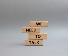 We need to talk symbol. Concept words We need to talk on wooden blocks. Beautiful grey background....