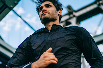 Below view of sportsman dressed in active wear for workout running at speed in urban setting.Motivated male jogger in active wear training outdoors on bridge for healthy vitality