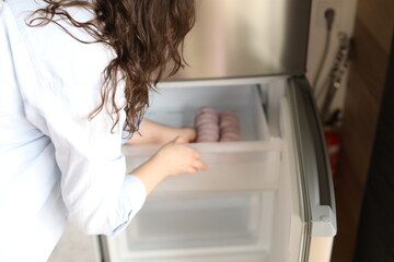 young woman takes frozen cottage cheese pancakes from the freezer on the table, frozen food