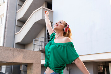 happy woman wearing headphones and smiling in the city. listening to music with headphones