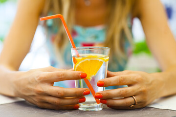 A vibrant scene capturing a woman savoring a chilled drink with a slice of orange, highlighting a...